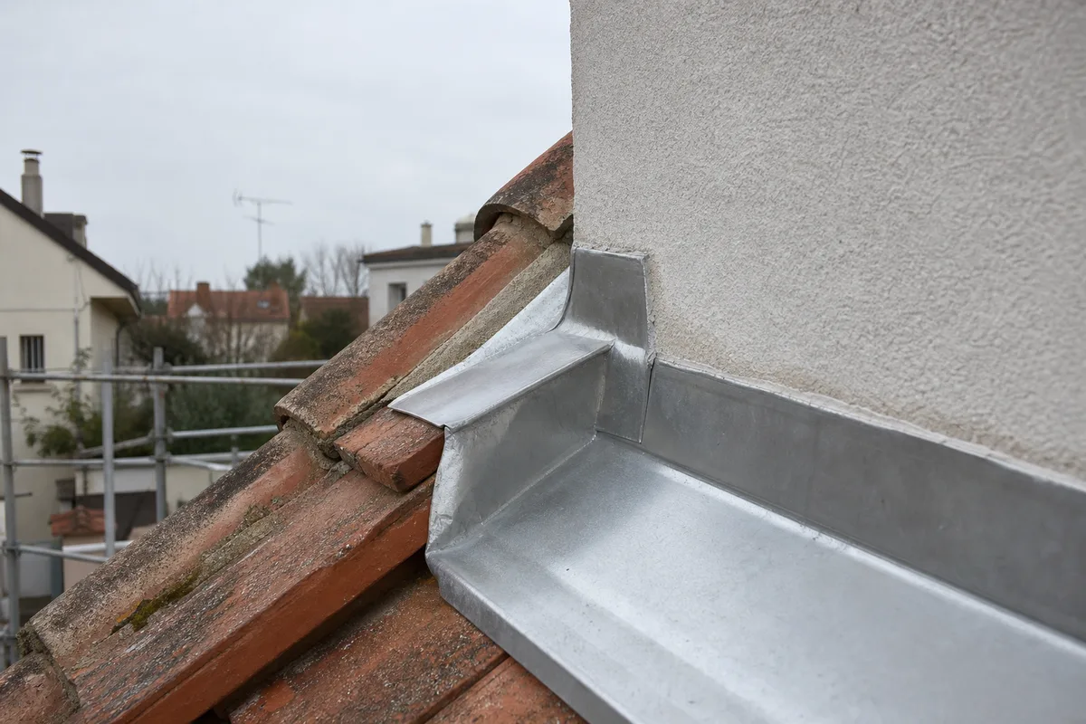 Couvreur inspectant les tuiles béton d’un pavillon du Val-d’Oise depuis un échafaudage