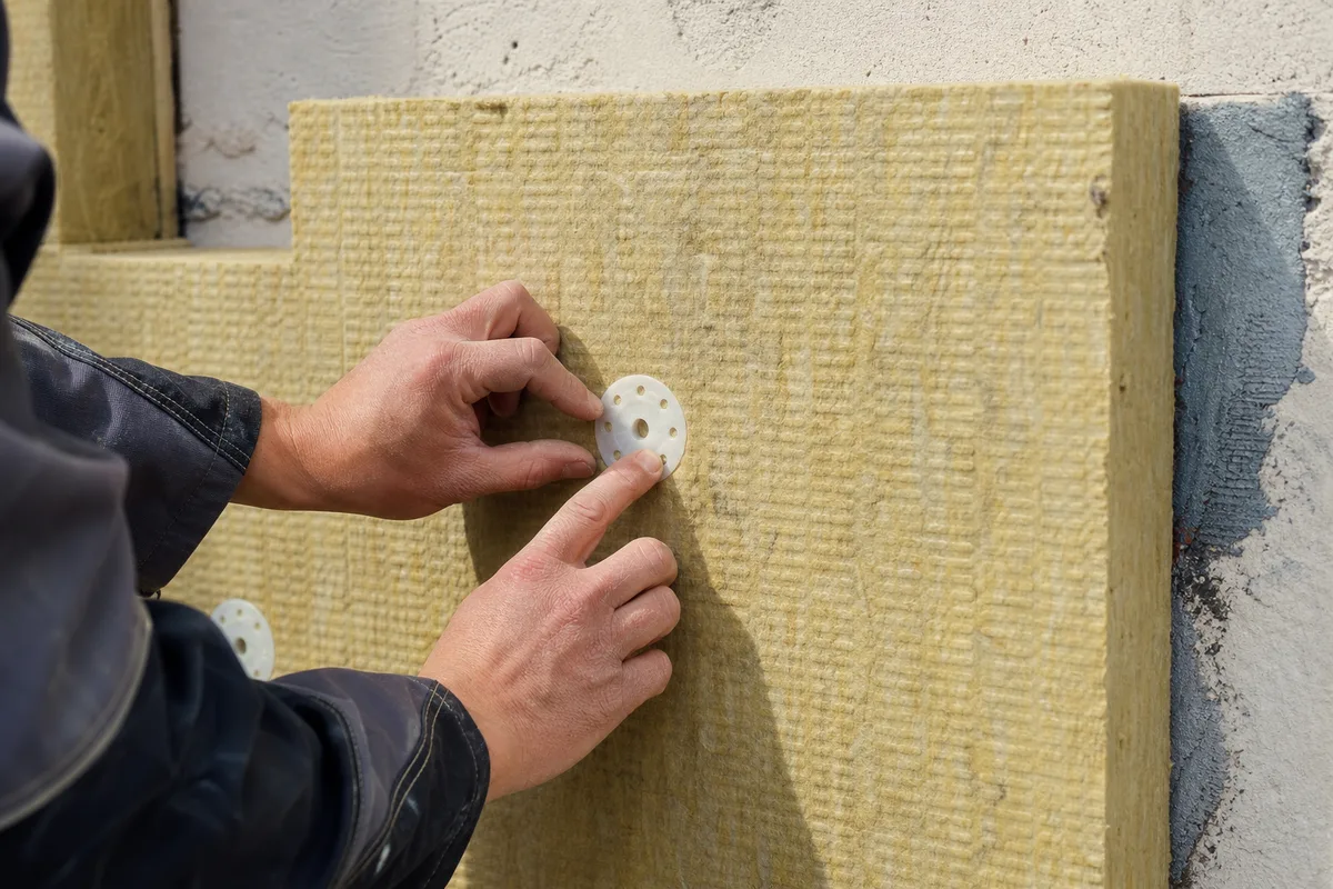 Pose de panneaux isolants gris sur la façade d’un pavillon francilien depuis un échafaudage